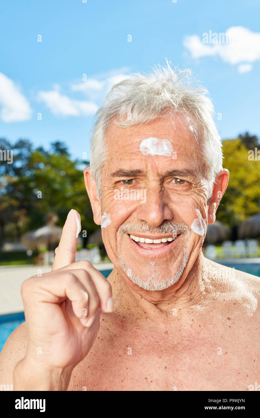 Älterer Mann im Urlaub Cremes sein Gesicht mit Sonnencreme als Haut protector Stockfoto