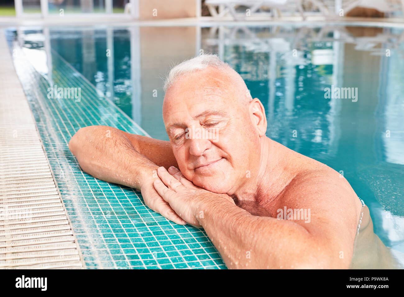 Erschöpft älterer Mann entspannt am Rand des Pool im Wellness Hotel Stockfoto