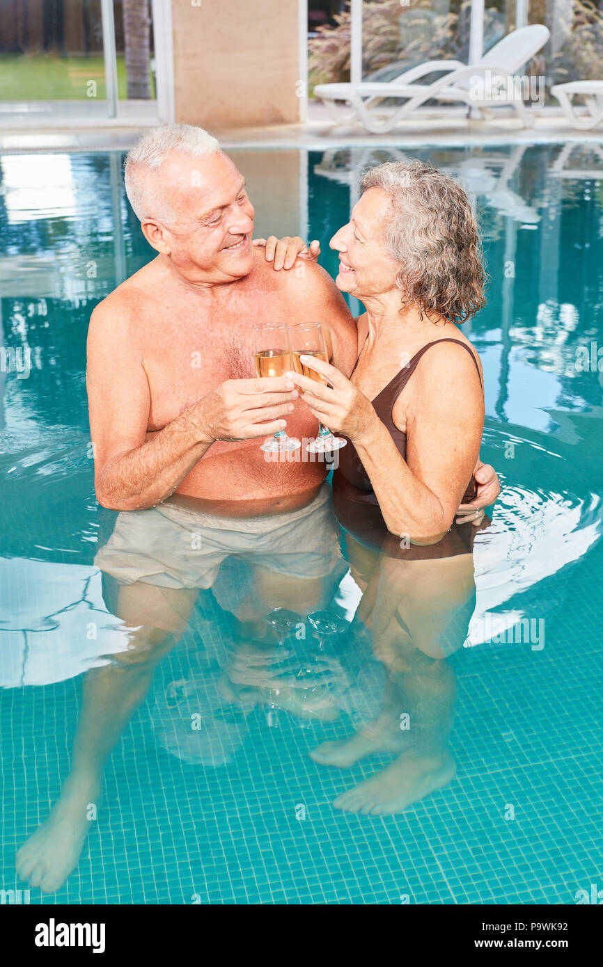 Happy Senioren Paar feiern mit Sekt im Schwimmbad im Spa Hotel Stockfoto