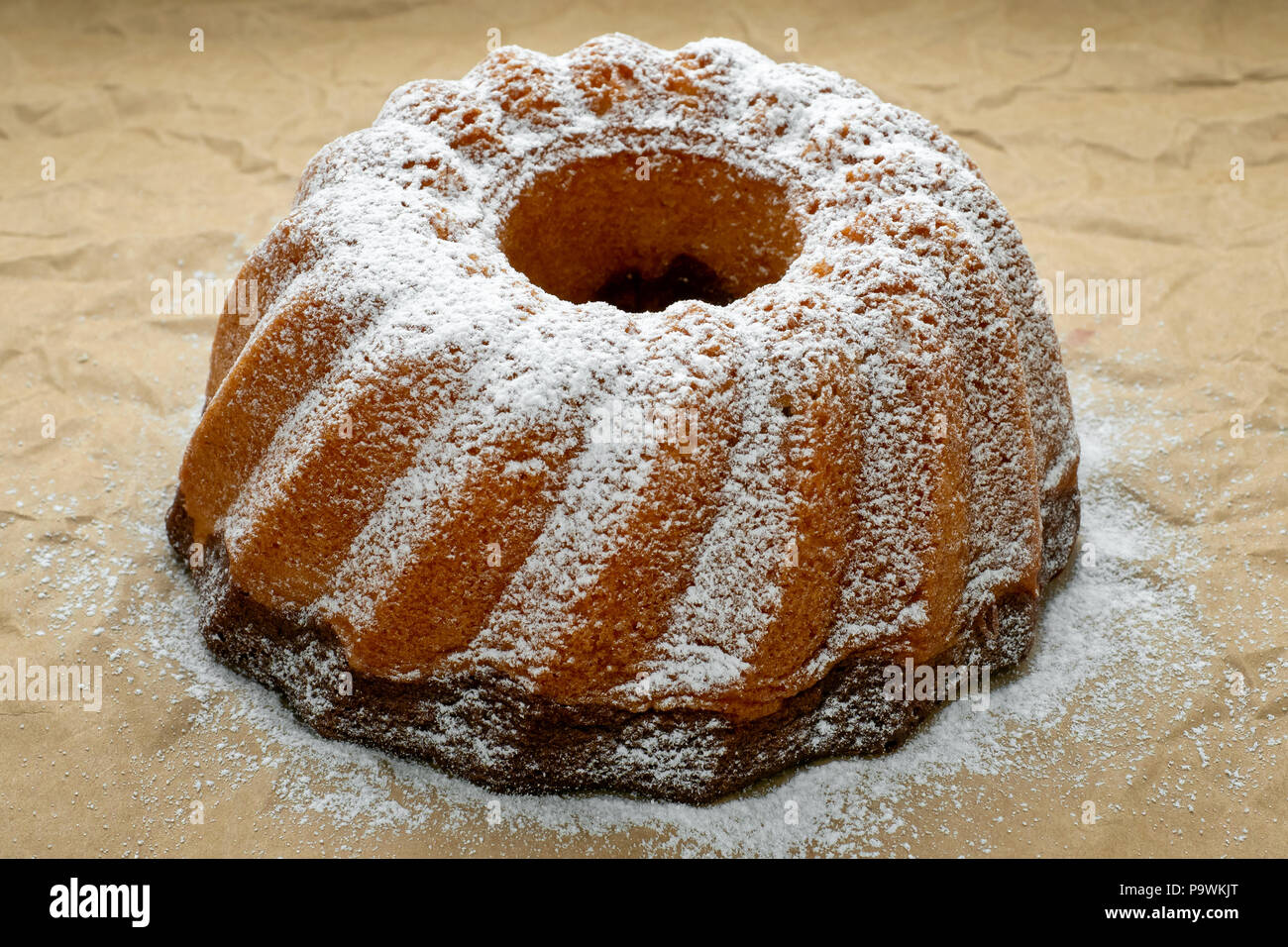 Zu Hause frisch gebackene ganze Marmor Kuchen mit Puderzucker auf Papier abgedeckt. Stockfoto