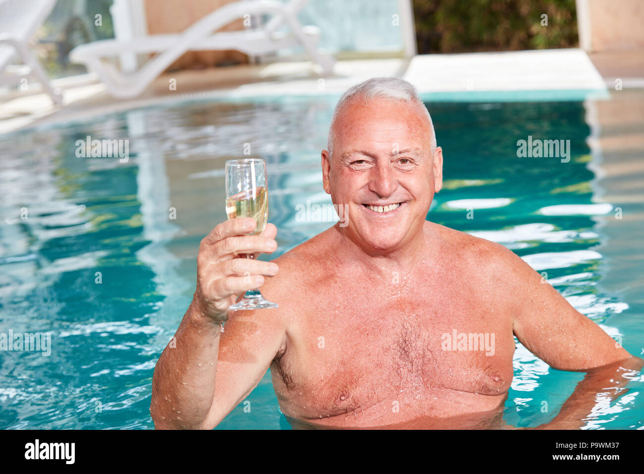 Lächelnd älterer Mann im Pool mit einem Glas Champagner im Wellness Hotel Stockfoto