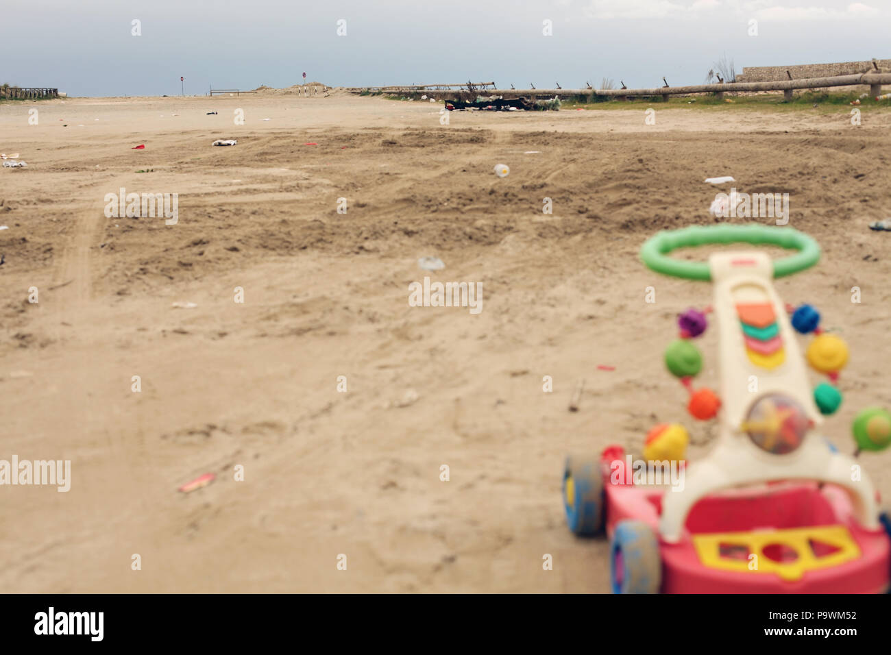 Eine verlassene alte Kunststoff Spielzeug an einem Sandstrand voller Müll und Schmutz. Kopieren Space Shot. Wüst, Traurigkeit, Erinnerungen. Stockfoto