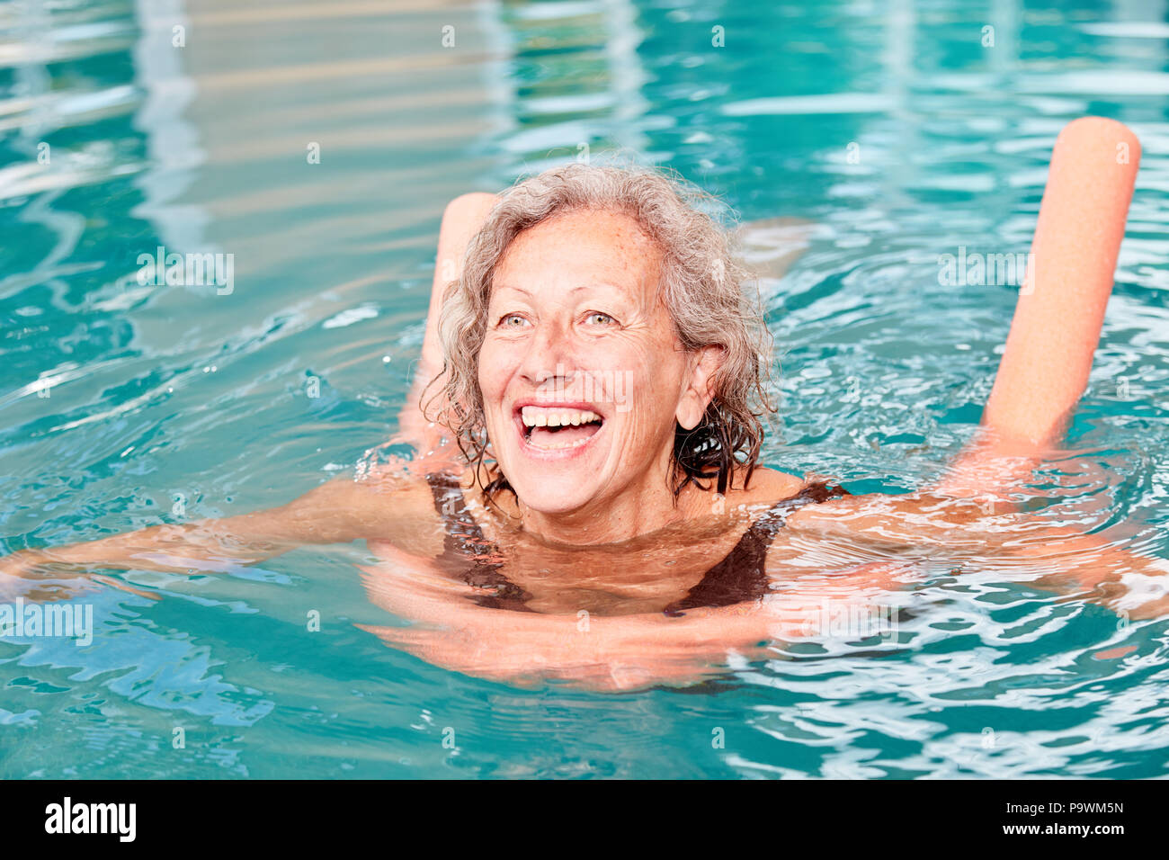 Active Senior Frau ist Spaß mit Wassergymnastik im Pool mit einer Schwimmweste Stockfoto