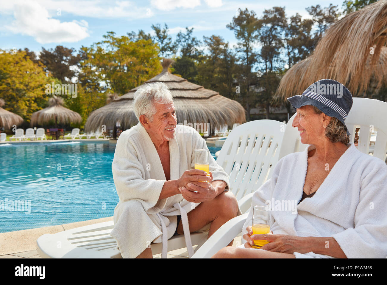 Gerne älteres Paar erfrischt sich mit Orangensaft am Pool im Spa Hotel Stockfoto