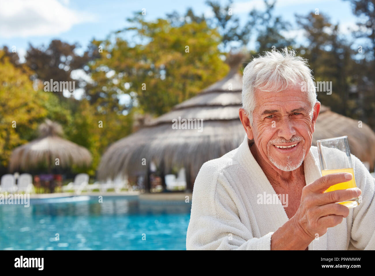 Gerne älterer Mann getränke Orangensaft am Pool während der Wellness Urlaub Stockfoto