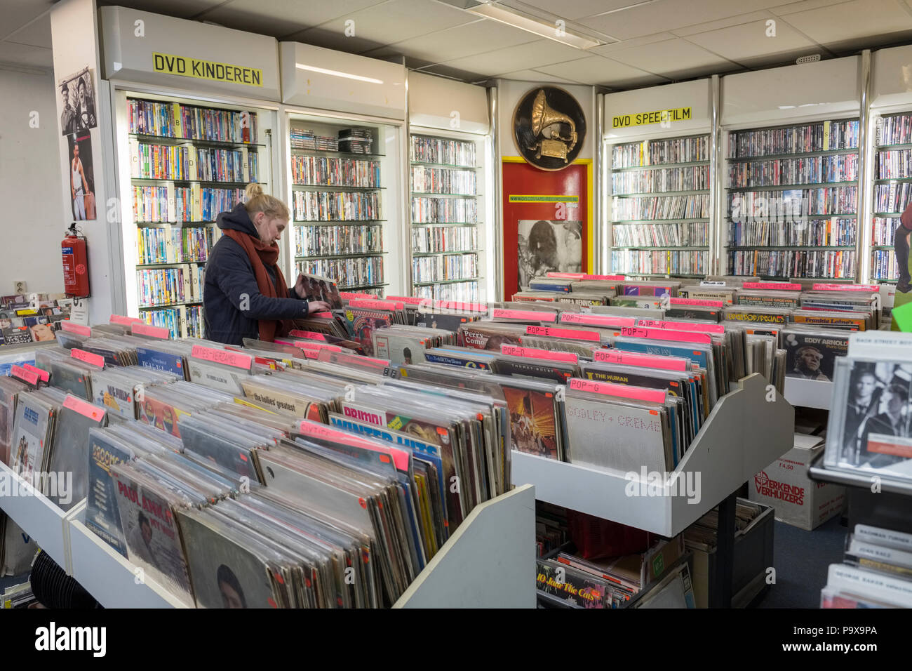 Junge Frau surfen Schallplatten und Alben in den Regalen in einem Plattenladen und DVD Store Innenraum, Amsterdam, Niederlande, Holland, Europa Stockfoto