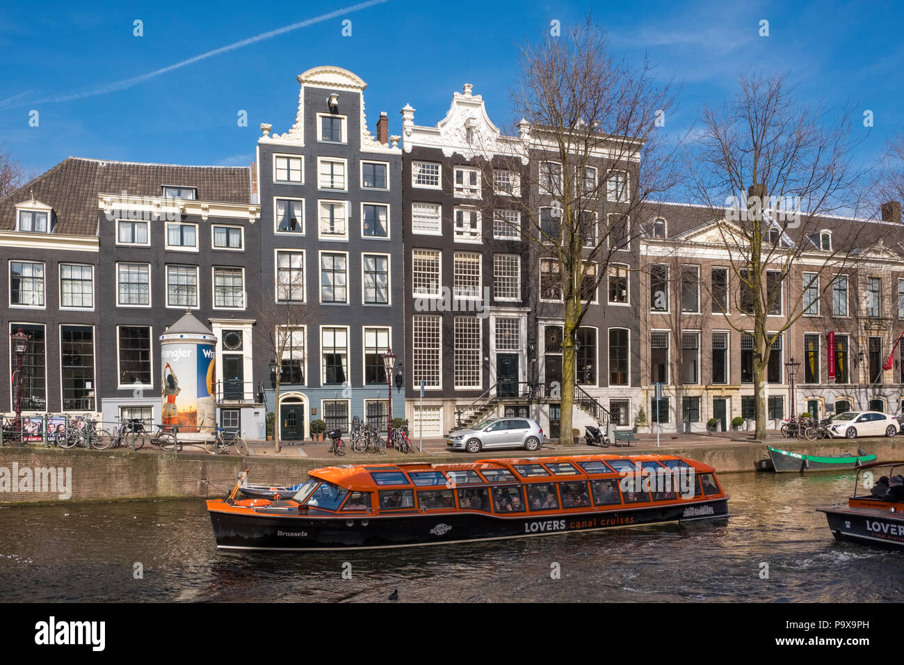 Schiff an einer Gracht in Amsterdam, Niederlande, Europa mit traditionellen Grachtenhäuser hinter Stockfoto