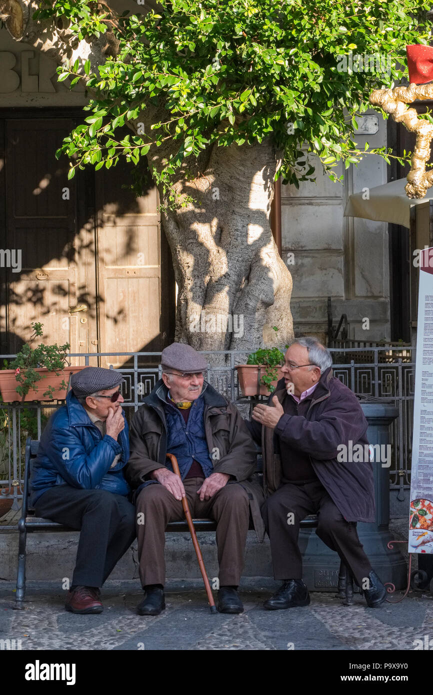 Drei alte Männer im Gespräch im Gespräch auf einer Bank auf dem Marktplatz, Cefalu, Sizilien, Italien, Europa Stockfoto