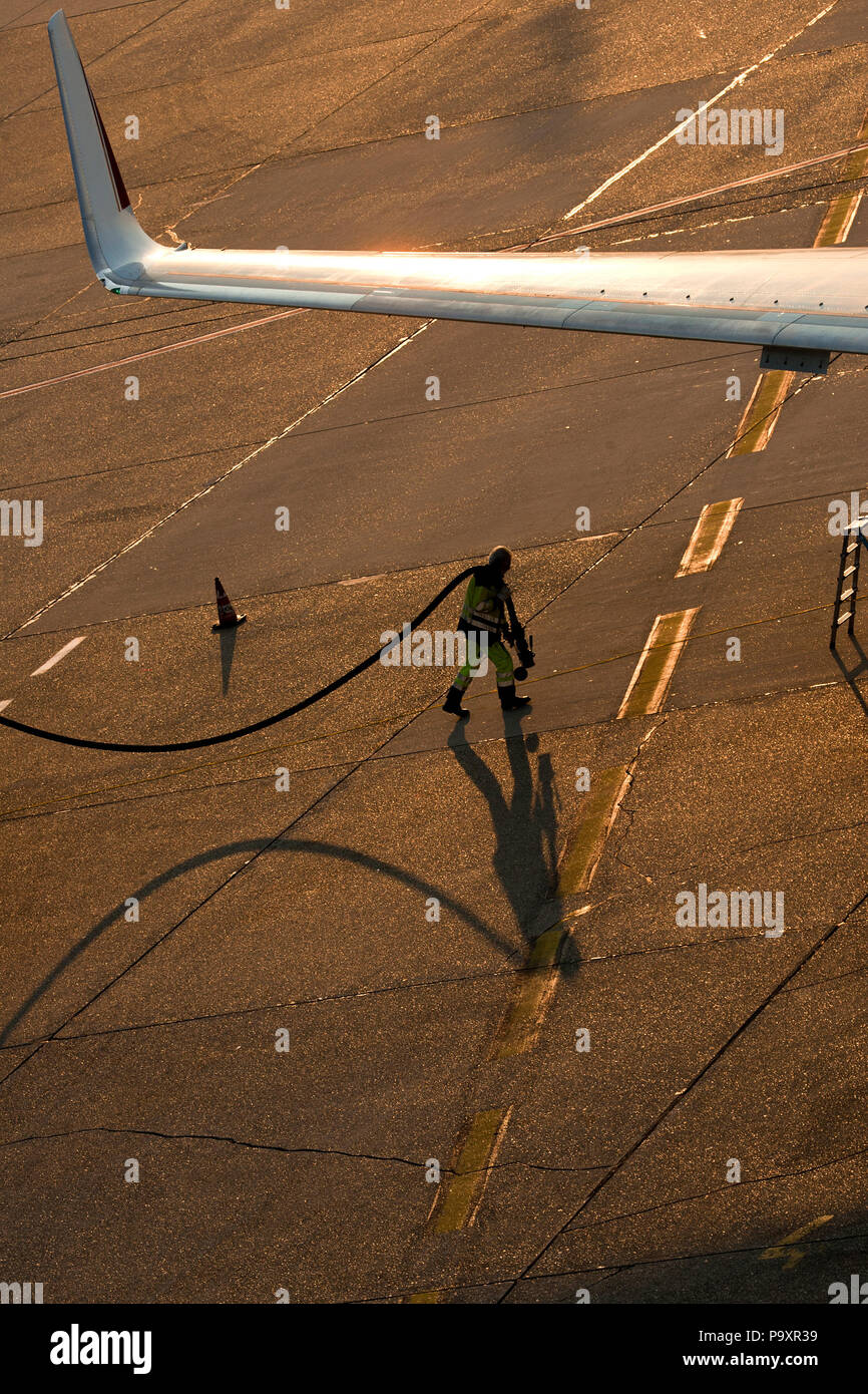Ein Flughafen serviceman Spaziergänge unter dem Flügel einer Boeing-737 das Flugzeug vor der Reise am Flughafen Düsseldorf, Deutschland zu tanken. Stockfoto