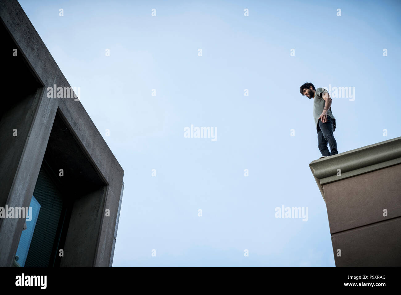 Ansicht von unten der männlichen parkour Sportler stehen auf dem Dach Stockfoto