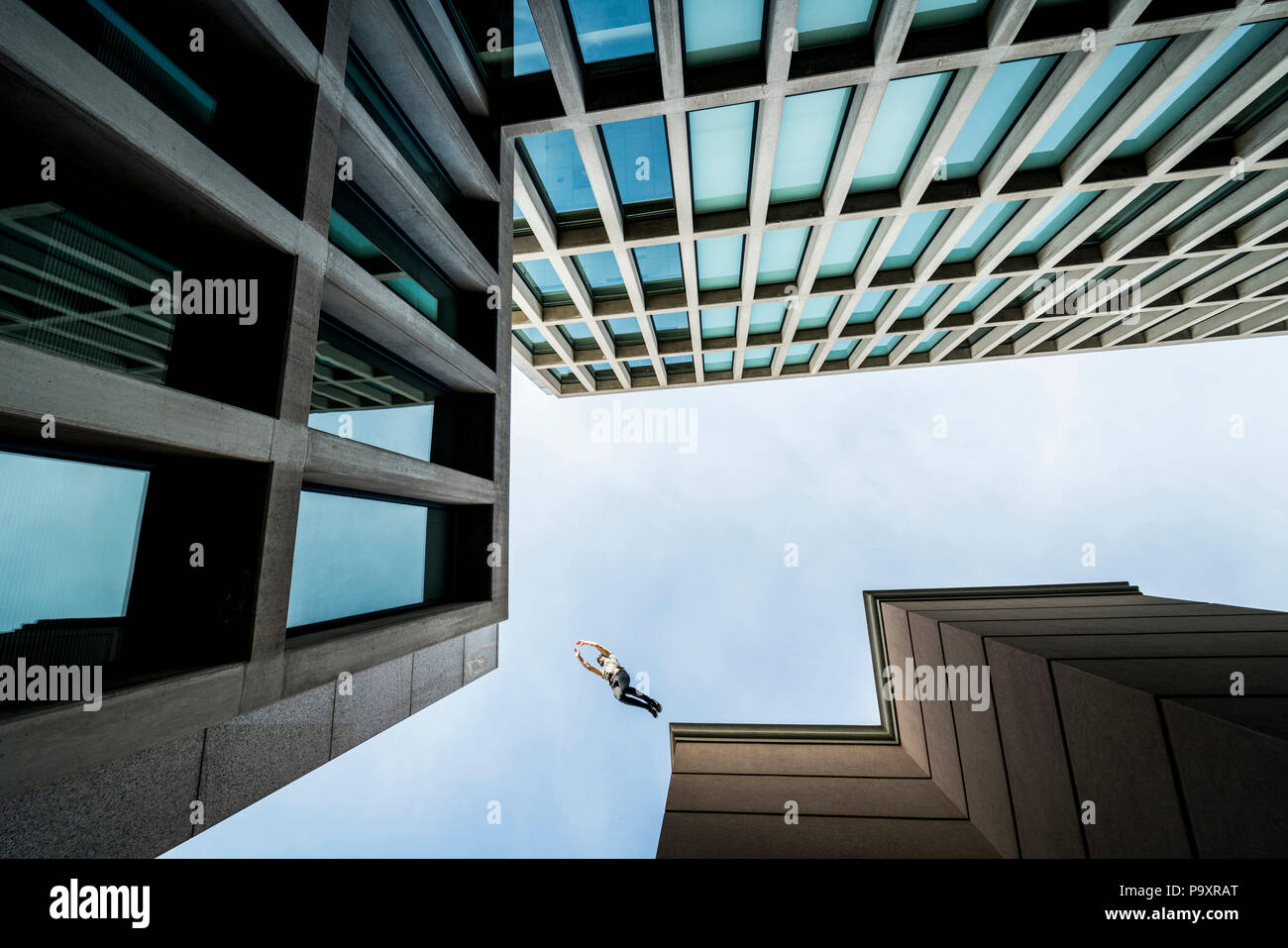 Ansicht von unten der männlichen parkour Sportler von einem Dach zum anderen springen Stockfoto