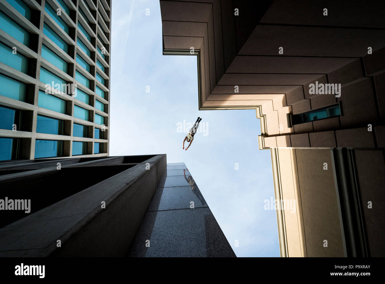 Ansicht von unten der männlichen parkour Sportler von einem Dach zum anderen springen Stockfoto