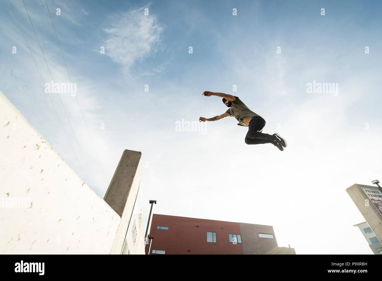 Seitenansicht des einzigen männlichen parkour Sportler von einer Wand zur anderen springen Stockfoto