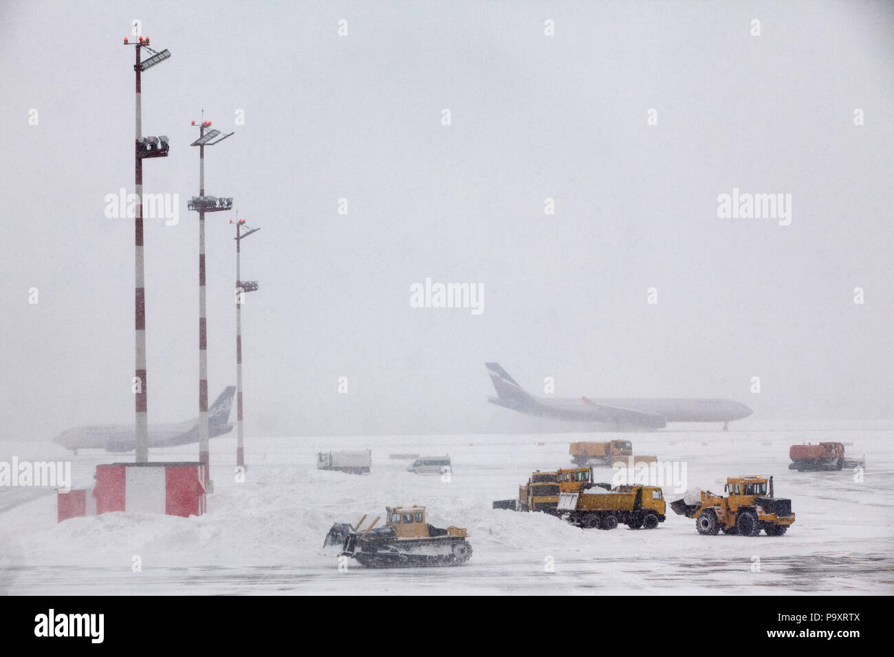 Der Asphalt von Moscow-Sheremetyevo Flughafen ist mit Schnee bedeckt, wie ein Schneesturm zu Verzögerungen und schlechten Wetterbedingungen die Rampe Reinigung team Kräfte Stockfoto