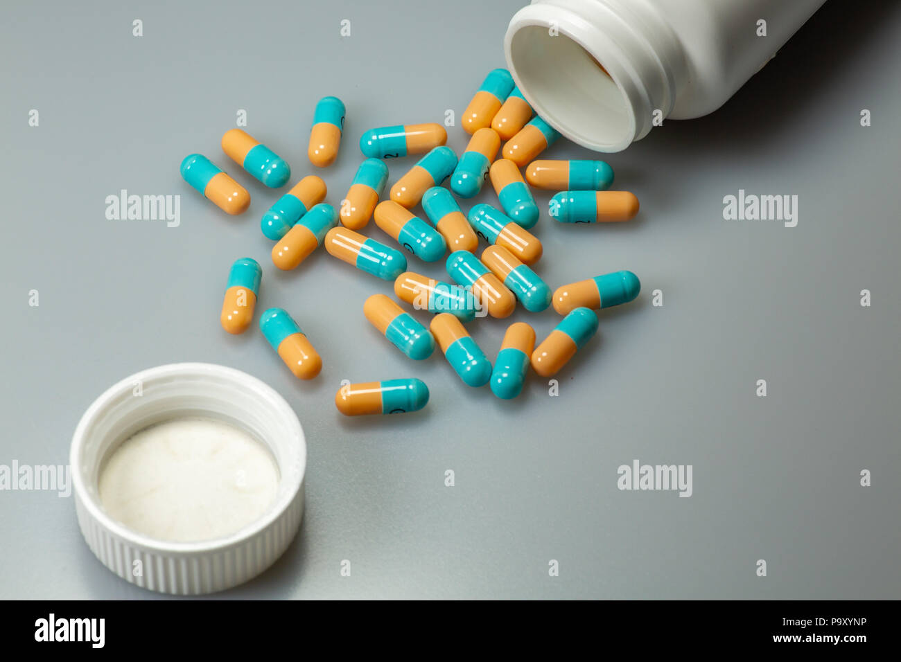 Gelbe und blaue Pillen aus einer weißen Flasche auf der Apotheke Tabelle Stockfoto