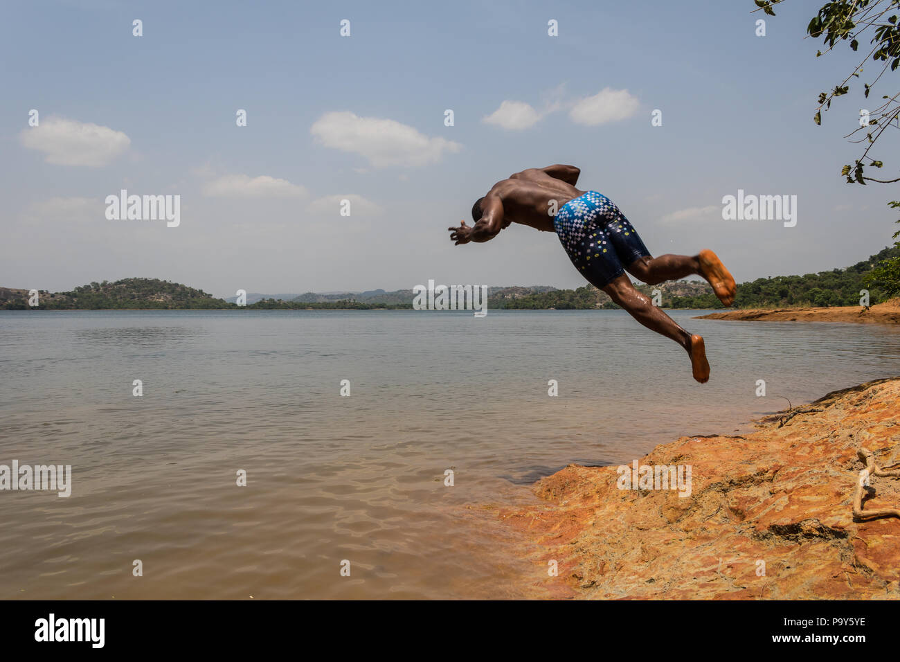 Eine junge muskulöse athletischen Mann nimmt einen Salto Eintauchen in den Fluss in den Morgen. Stockfoto