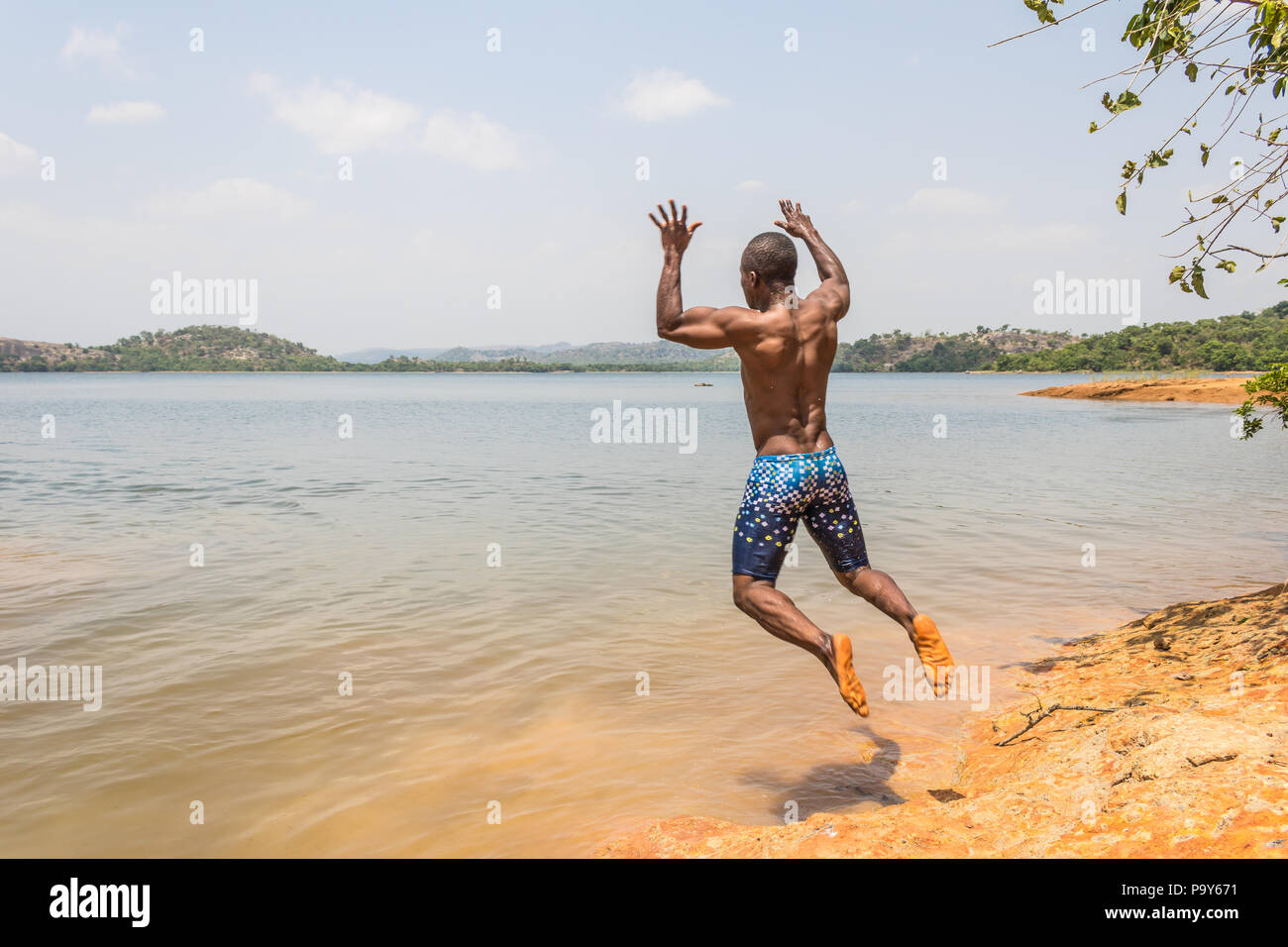 Eine junge muskulöse athletischen Mann nimmt einen Sprung in den Fluss in den Morgen. Stockfoto