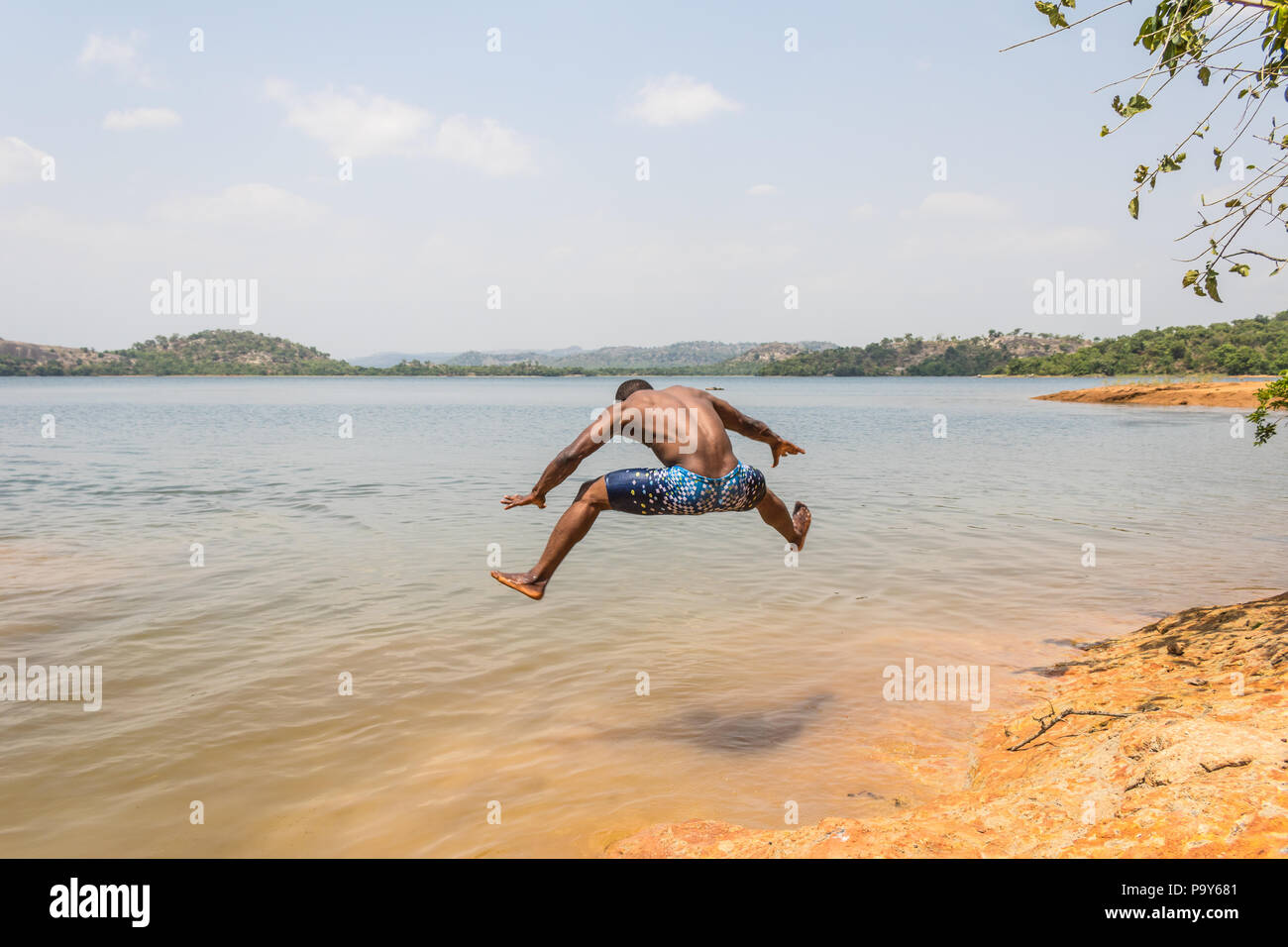 Eine junge muskulöse athletischen Mann nimmt einen Sprung in den Fluss in den Morgen. Stockfoto