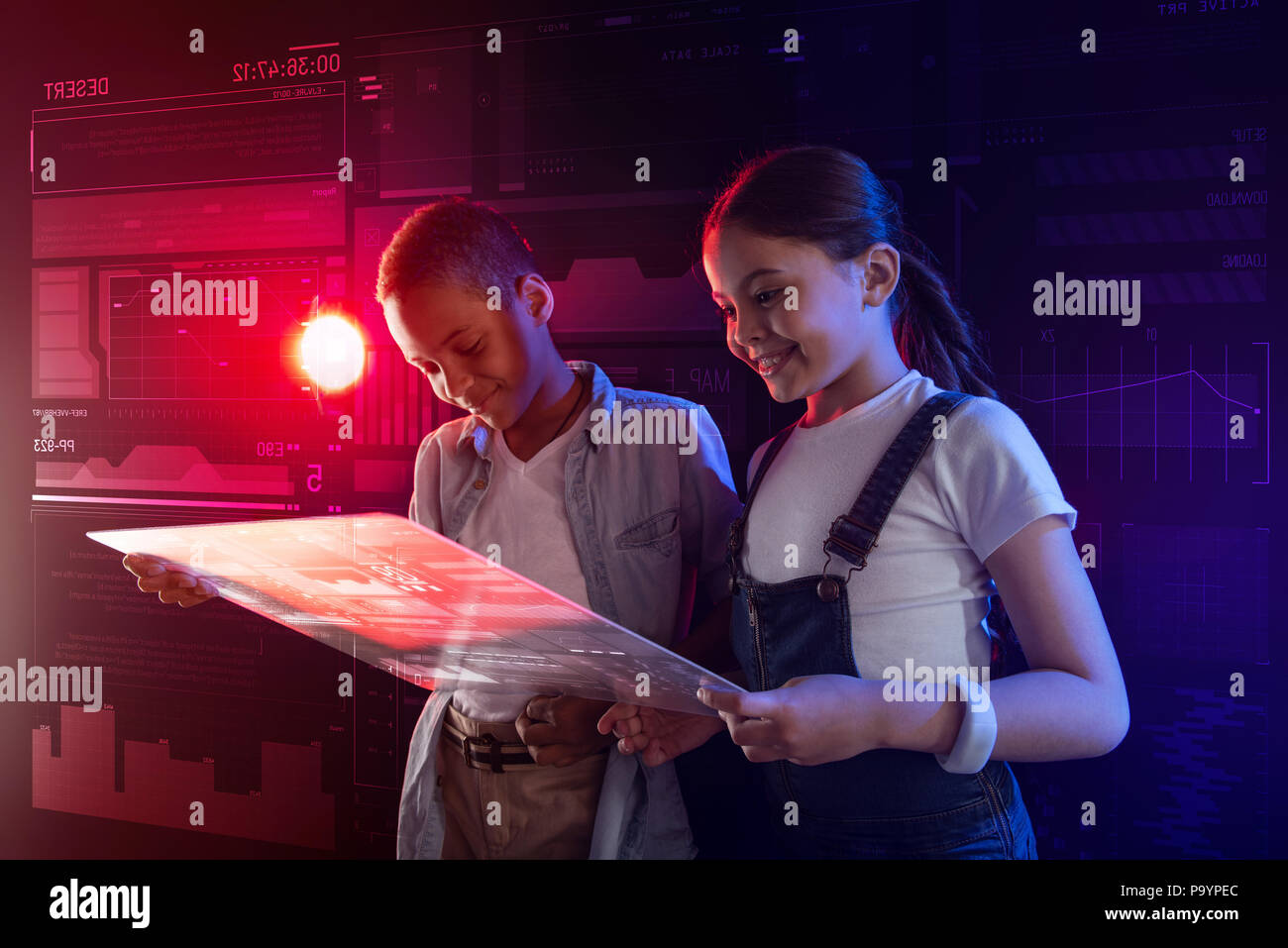 Positive Kinder lächeln und Gefühl von einem Gerät, das mit einer hellen Bildschirm beeindruckt. Stockfoto