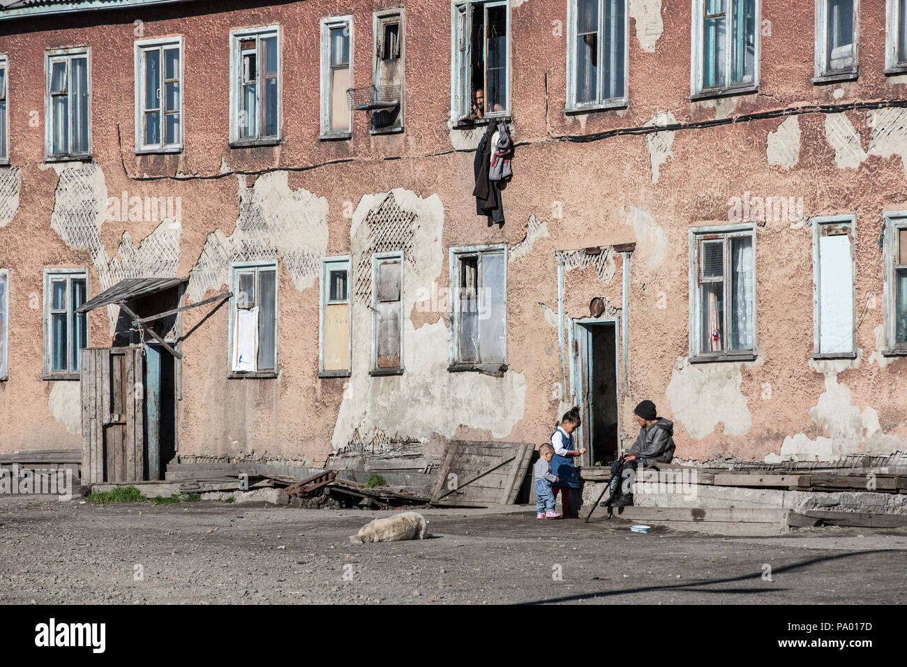 Die Einheimischen vor einem heruntergekommenen Gehäuse Block in Lorino, Tschukotka, Russland Stockfoto