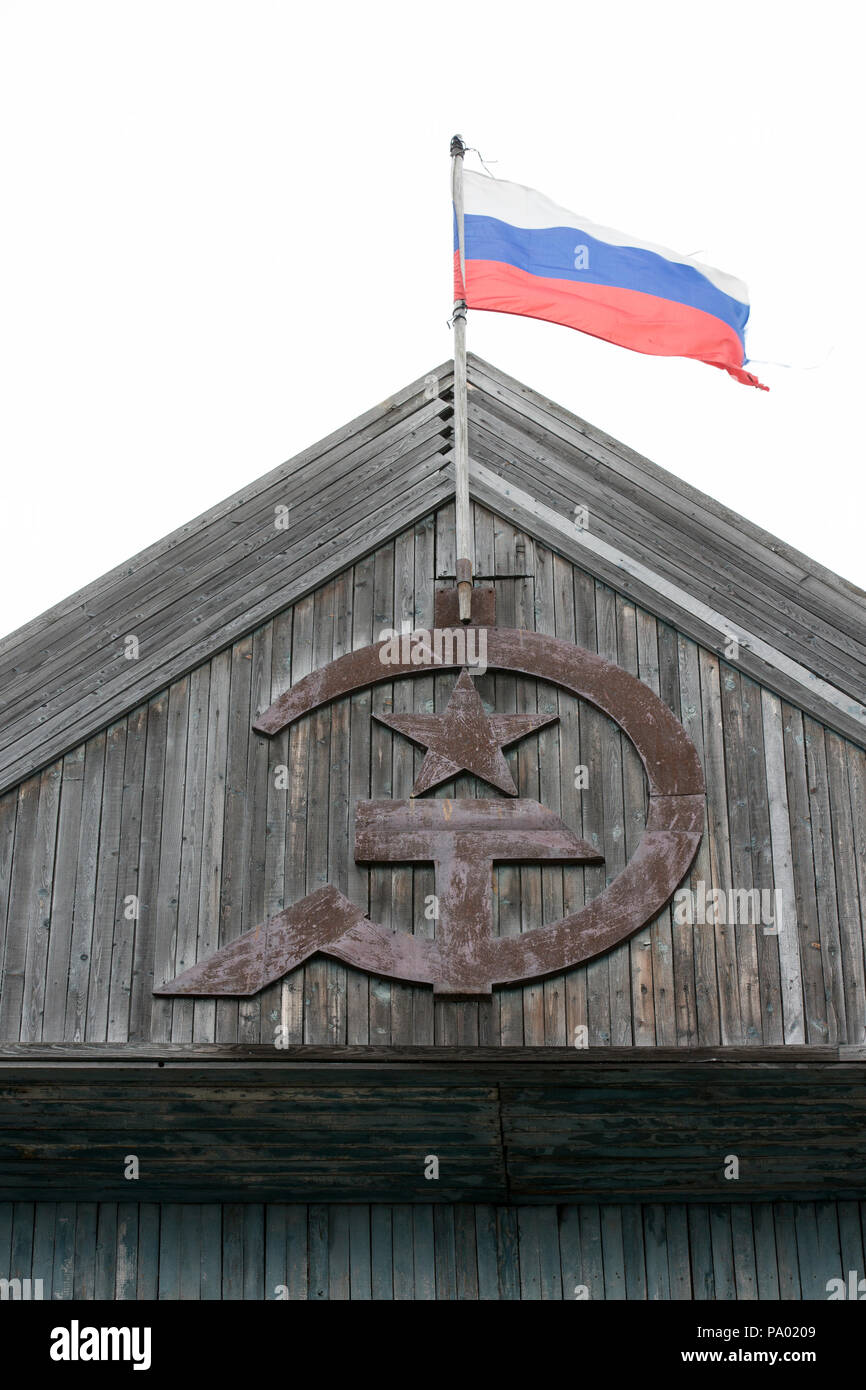 Russische Fahne über dem alten sowjetischen Hammer und Sichel in kleinen russischen Dorf in Kamtschatka Stockfoto