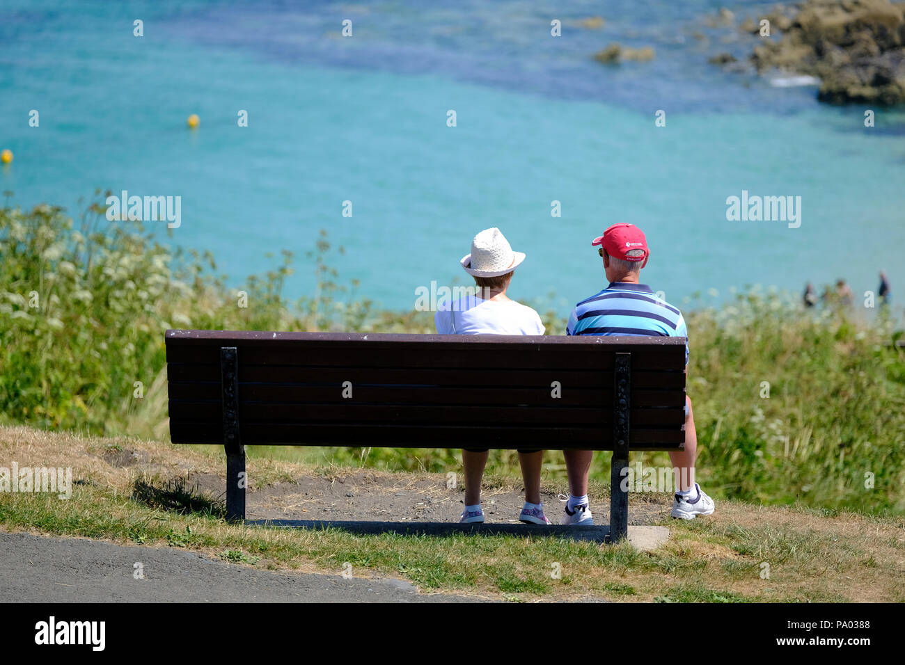Ältere Paare saß auf einer Bank im Gespräch mit Blick auf Porthgwidden Beach St Ives im Hintergrund Stockfoto