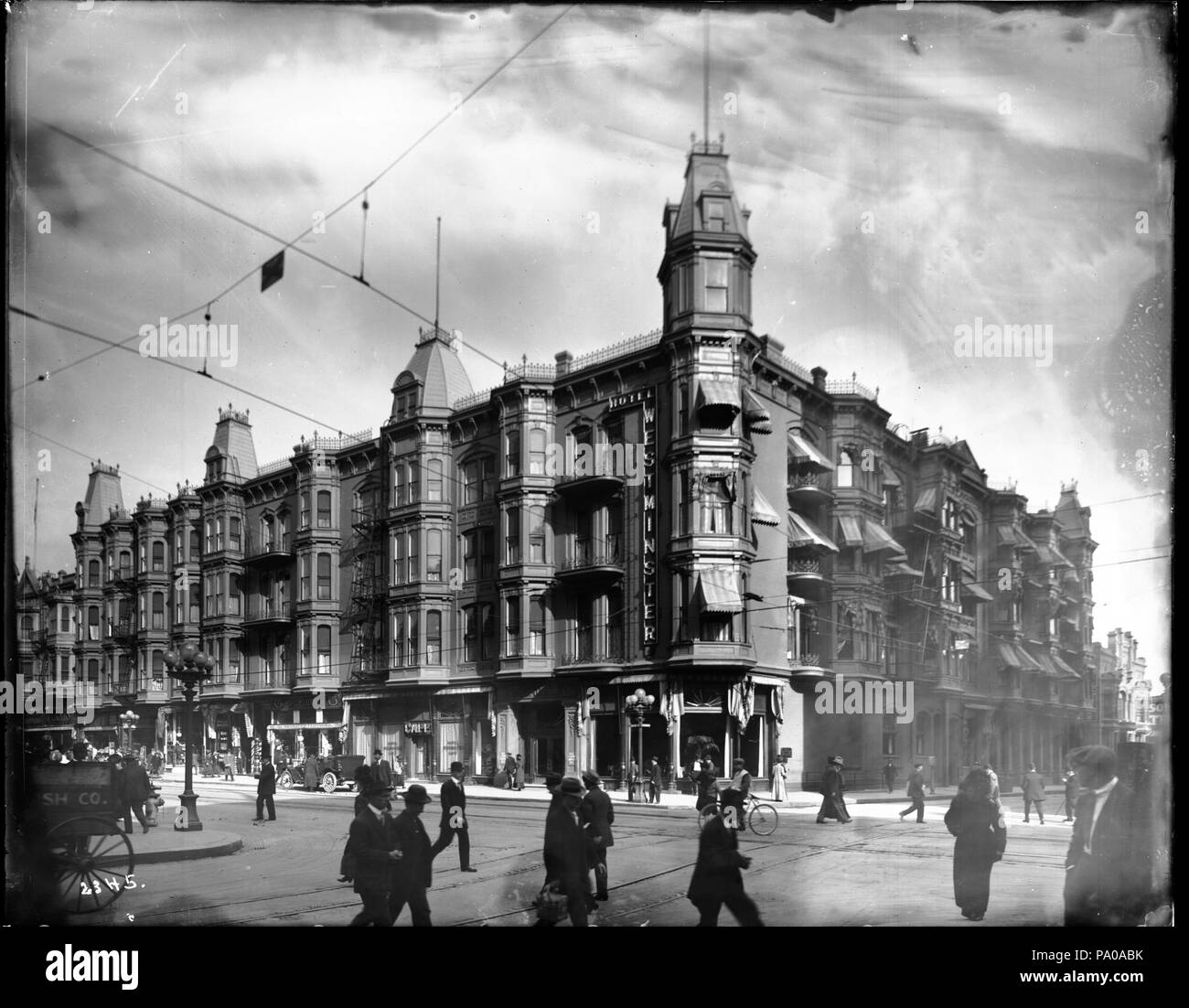 . Englisch: Äußere des Westminster Hotel an der Ecke der Fourth Street und Main Street, Los Angeles, Ca. 1900 Foto von der Außenseite des Westminster Hotel an der Ecke der Fourth Street und Main Street, Los Angeles, Ca 1900. Die 4-stöckige viktorianische Backsteingebäude verfügt über einen 6-stöckigen Turm an der Ecke über dem Haupteingang. Es gibt Markisen auf Straßenebene. Ein Auto ist am Strassenrand geparkt, während ein Radfahrer radeln durch ist. Teil einer Pferdewagen ist auf der linken Seite sichtbar. Zahlreiche Fußgänger überqueren der Straße. Straßenbahn Schienen und Freileitungen sind sichtbar. Bein Stockfoto