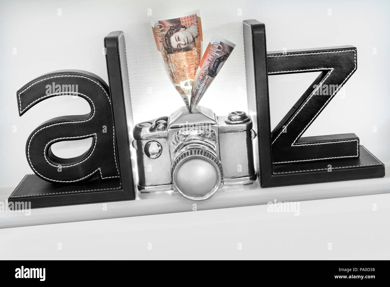 Konzept A-Z Geld von Ihrer Kamera 'Fotografie Bilder, die verkaufen. £ 10 Notizen in Einsparungen Schlitz in der oberen Konzept Stil silber Kamera Stockfoto