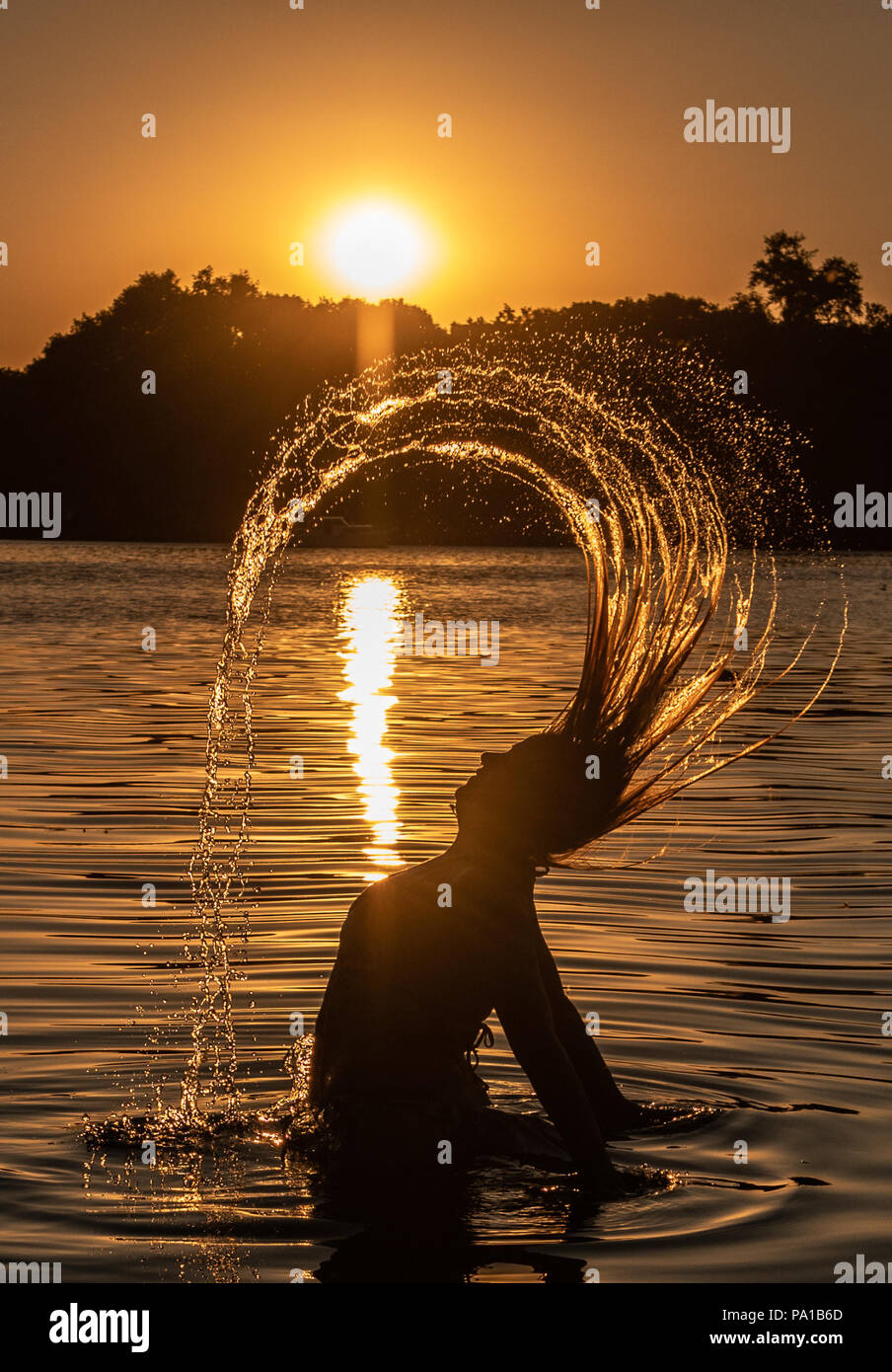 19 Juli 2018, Germany, Berlin: Jennifer, erkennbar nur als Silhouette, unter der Sonne Licht im Tegelersee See. Foto: Paul Zinken/dpa | Verwendung weltweit Stockfoto