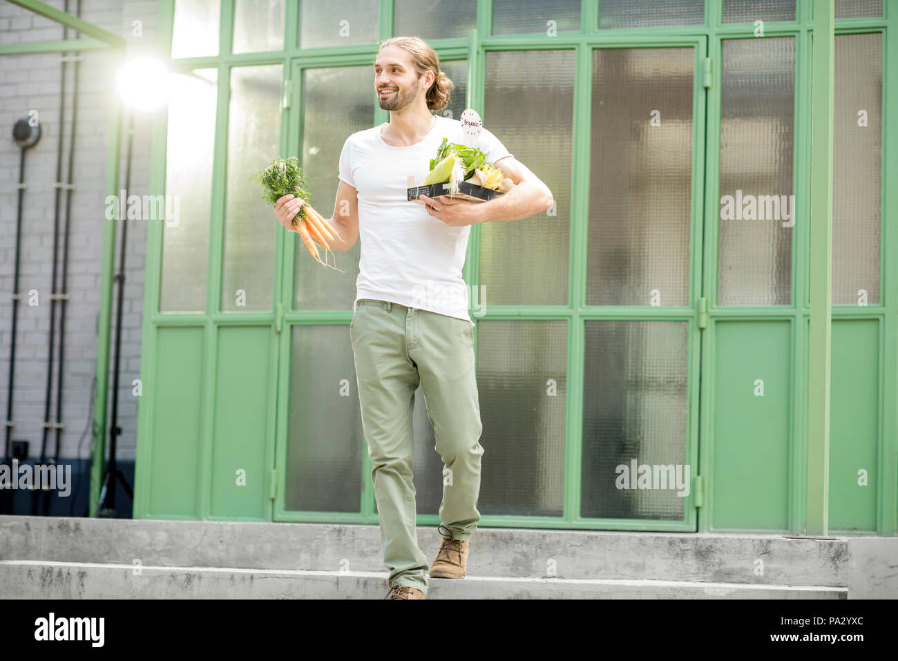 Mann, der Kiste voller Frische rohe Gemüse nur auf dem lokalen Markt im Freien auf der grünen Hintergrund gekauft Stockfoto