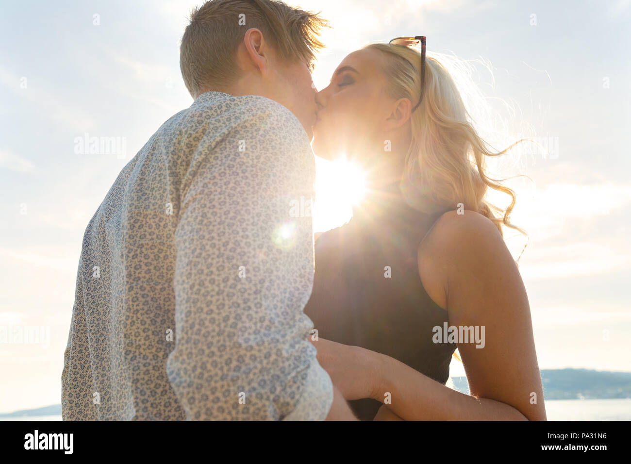 Romantisches Paar küssen am Strand gegen die Sonne Stockfoto