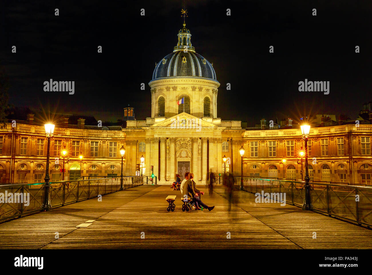 Pont des Arts Brücke zu Institut de France Gebäude, einem Französischen gelehrten Gesellschaft Gruppe von fünf Akademien. Kreuzung Brücke Sicht mit den Leuten in Paris, Frankreich. Nacht Szene. Stockfoto