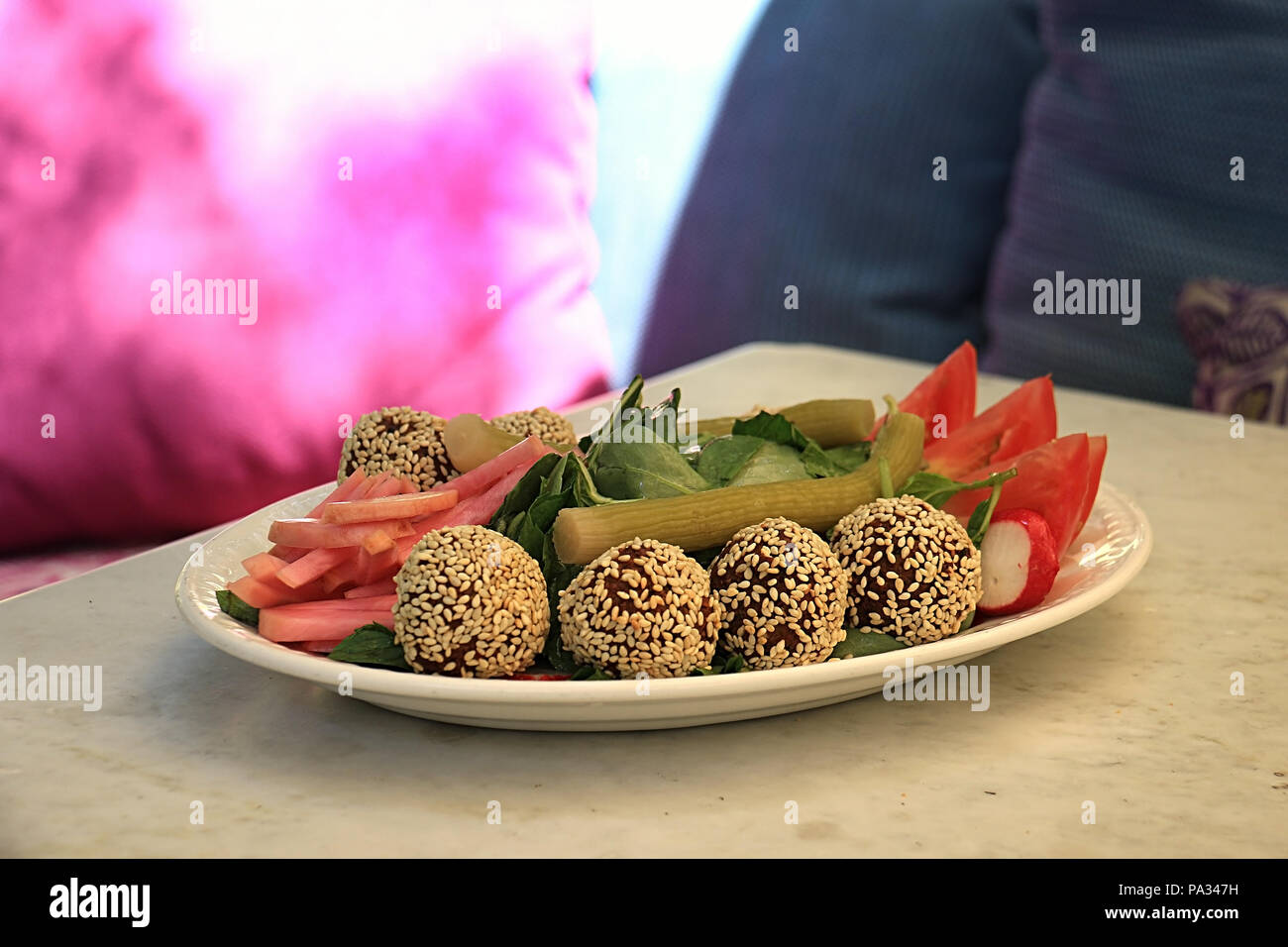 Falafelkugeln in Sesam in einer Schüssel zusammen mit der traditionellen begleitenden Gemüse abgedeckt. Stockfoto