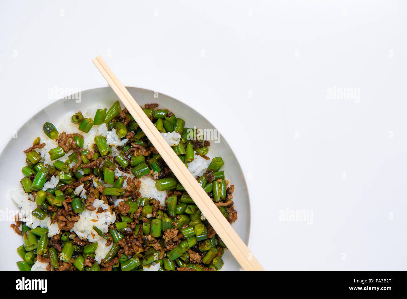 Schüssel mit Hackfleisch Eintopf mit Bohnen serviert über gekochten Reis mit Essstäbchen auf weißem Hintergrund Stockfoto