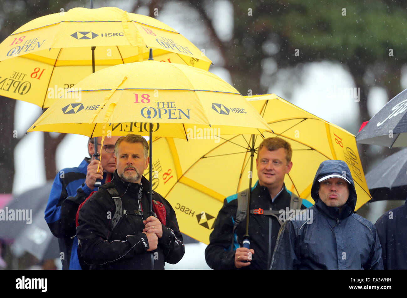 Fans Unterschlupf vor dem Regen, wie Sie die Aktion bei Tag zwei der Open Championship 2018 in Carnoustie Golf Links, Angus. Stockfoto