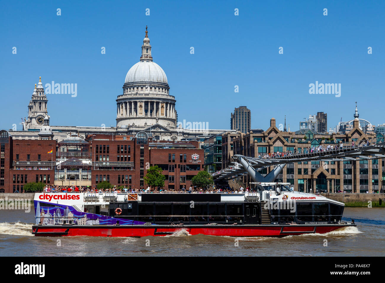 Eine Stadt Kreuzfahrten River Boat verläuft unter der Millennium Bridge, London, England Stockfoto