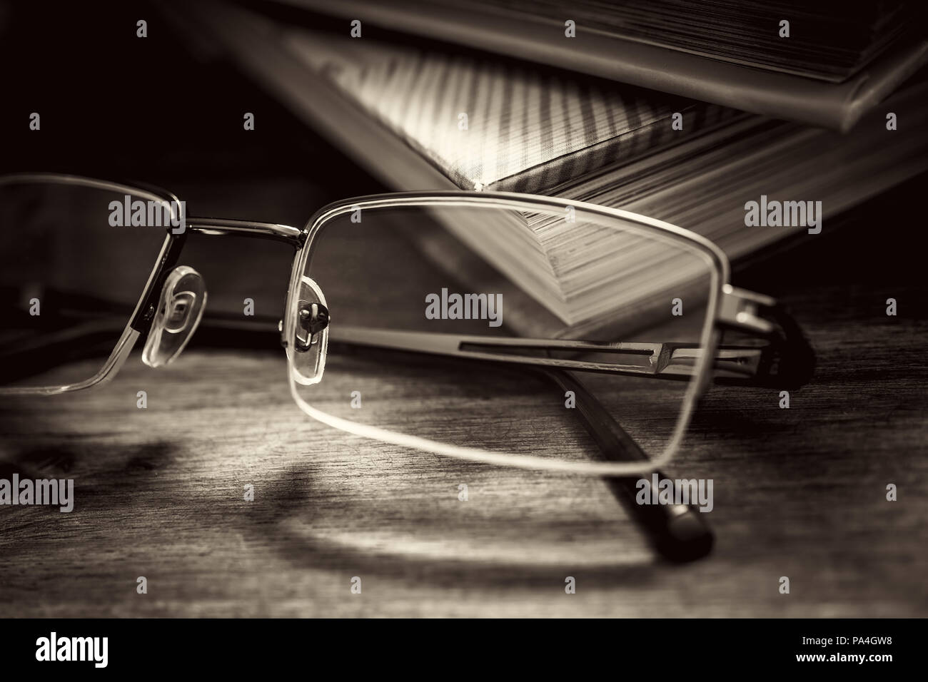 Brillen Vor einige Bücher auf hölzernen Tisch in Vintage Monochrome Farben Stockfoto
