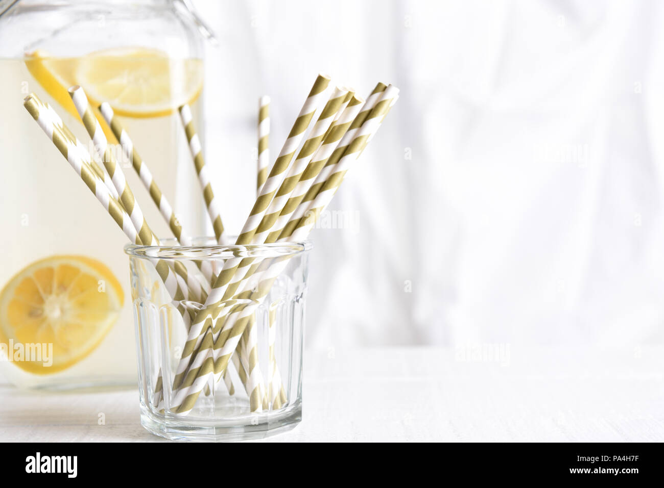 Sommer Limonade noch Leben: eine Limonade Krug mit einem Glas Trinkhalme vor der Küche Fenster. Horizontales Format mit kopieren. Fokus Stockfoto