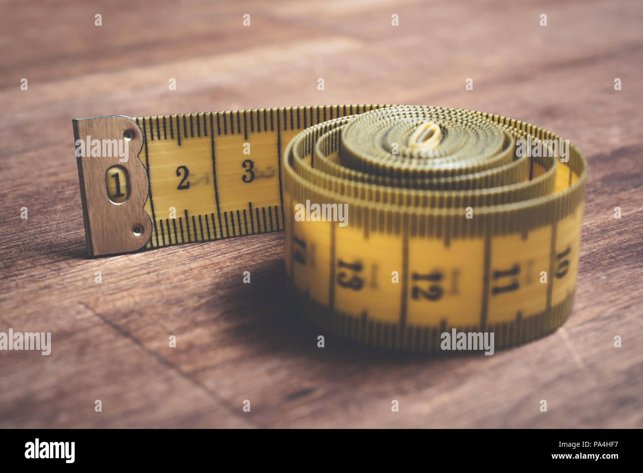 Makro einer Gelb Maßband auf einen hölzernen Tisch gewürfelt Stockfoto