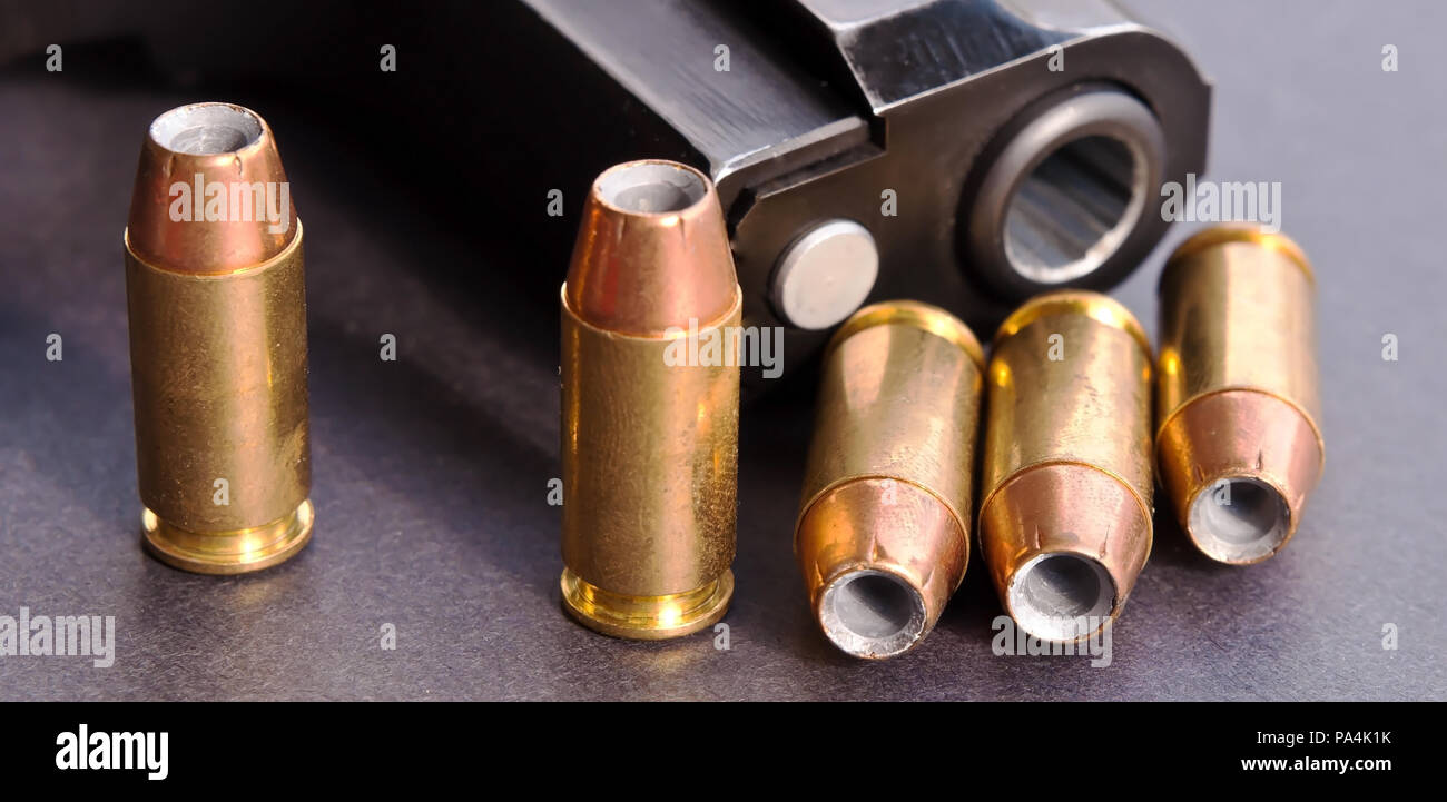 Fünf 40 Kaliber hollow point Punkte neben den Fang eines schwarzen Pistole auf einem schwarzen Hintergrund angezeigt Stockfoto