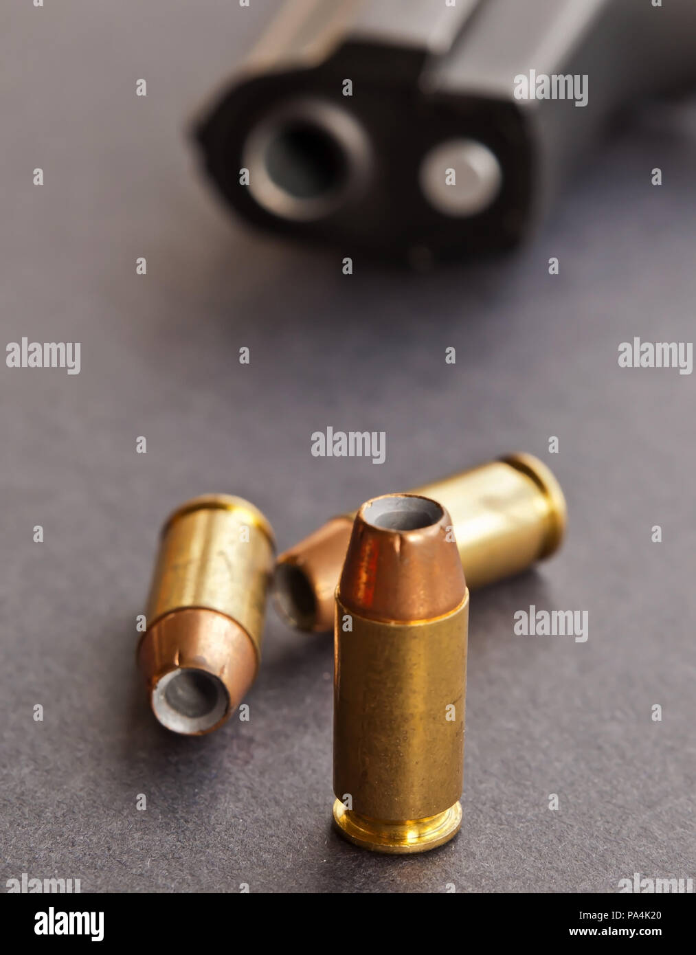 Drei 40 Kaliber hollow point Kugeln auf schwarzem Hintergrund mit einer schwarzen Pistole Verlegen hinter Ihnen nur die Schnauze angezeigt Stockfoto