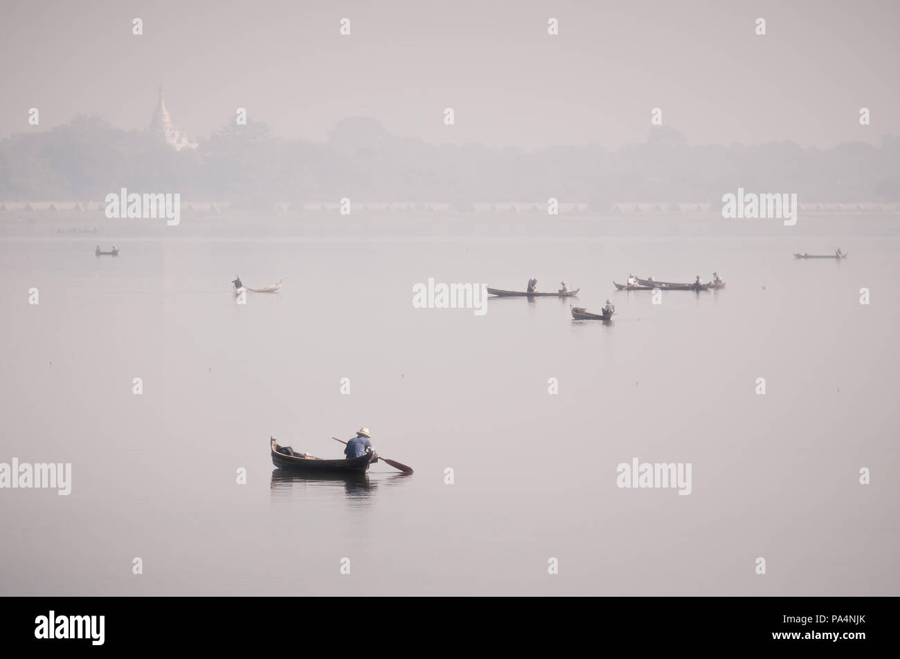 Boote mit Fischern auf der Taung Tha Mann See mit einer Pagode im Hintergrund während einer nebligen Wetter in Mandalay, Myanmar Stockfoto