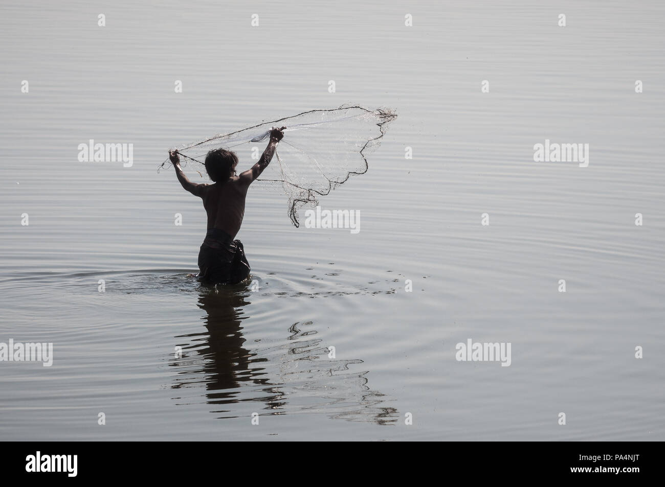 Ein Fischer in der Taung Tha Mann See wirft einen Fisch net im Wasser, Myanmar Stockfoto