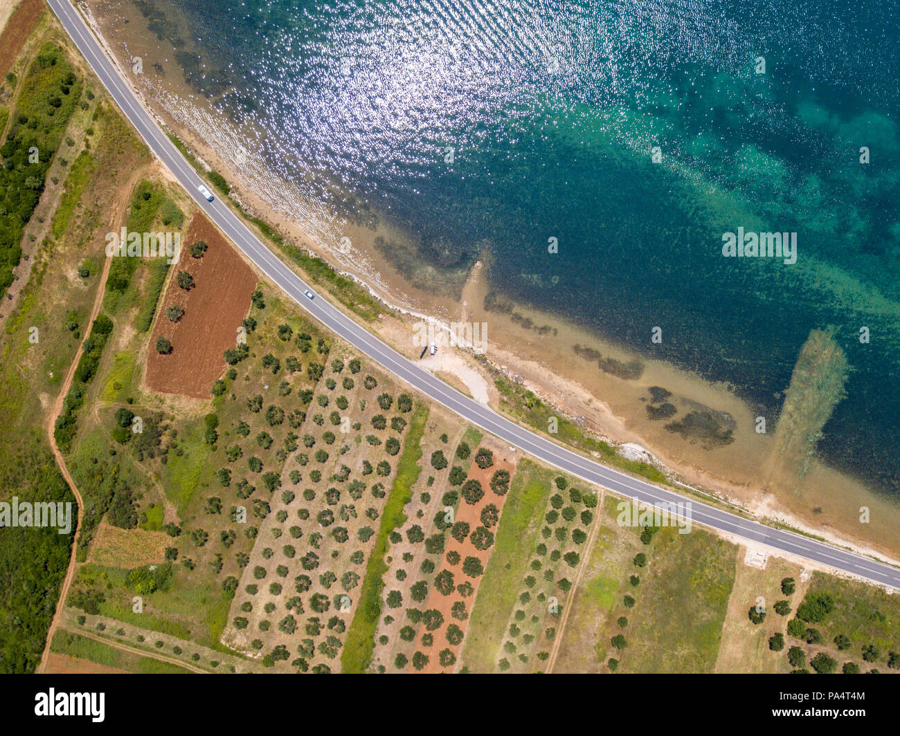 Luftaufnahme von einer Straße, die entlang der kroatischen Küste und durch landwirtschaftliche Felder läuft, mit Plantagen und Feldern. Küste Stockfoto