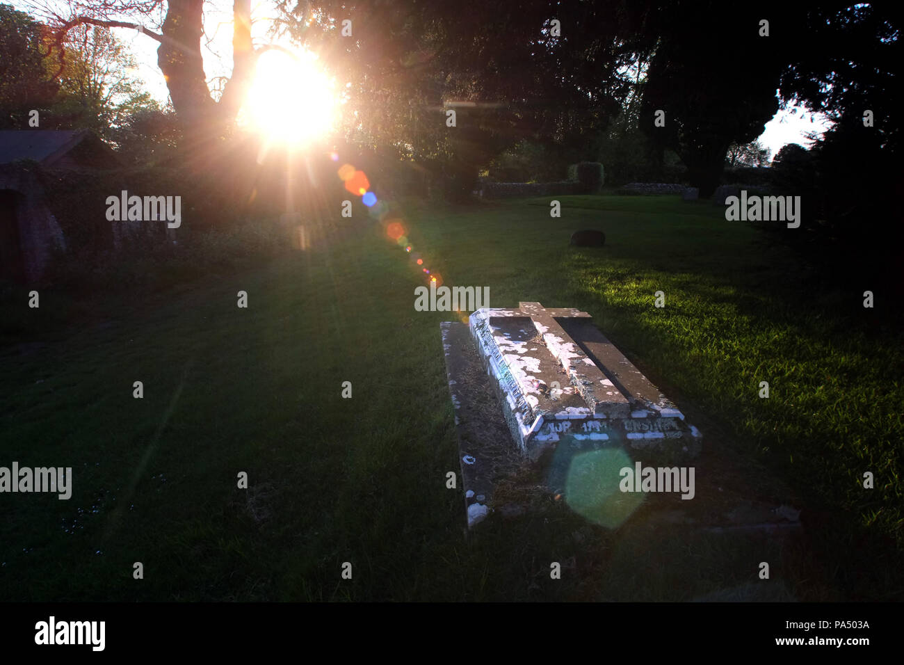 Sonnenstrahl erhellt ein Grab in einer Pfarrei Kirchhof. Stockfoto