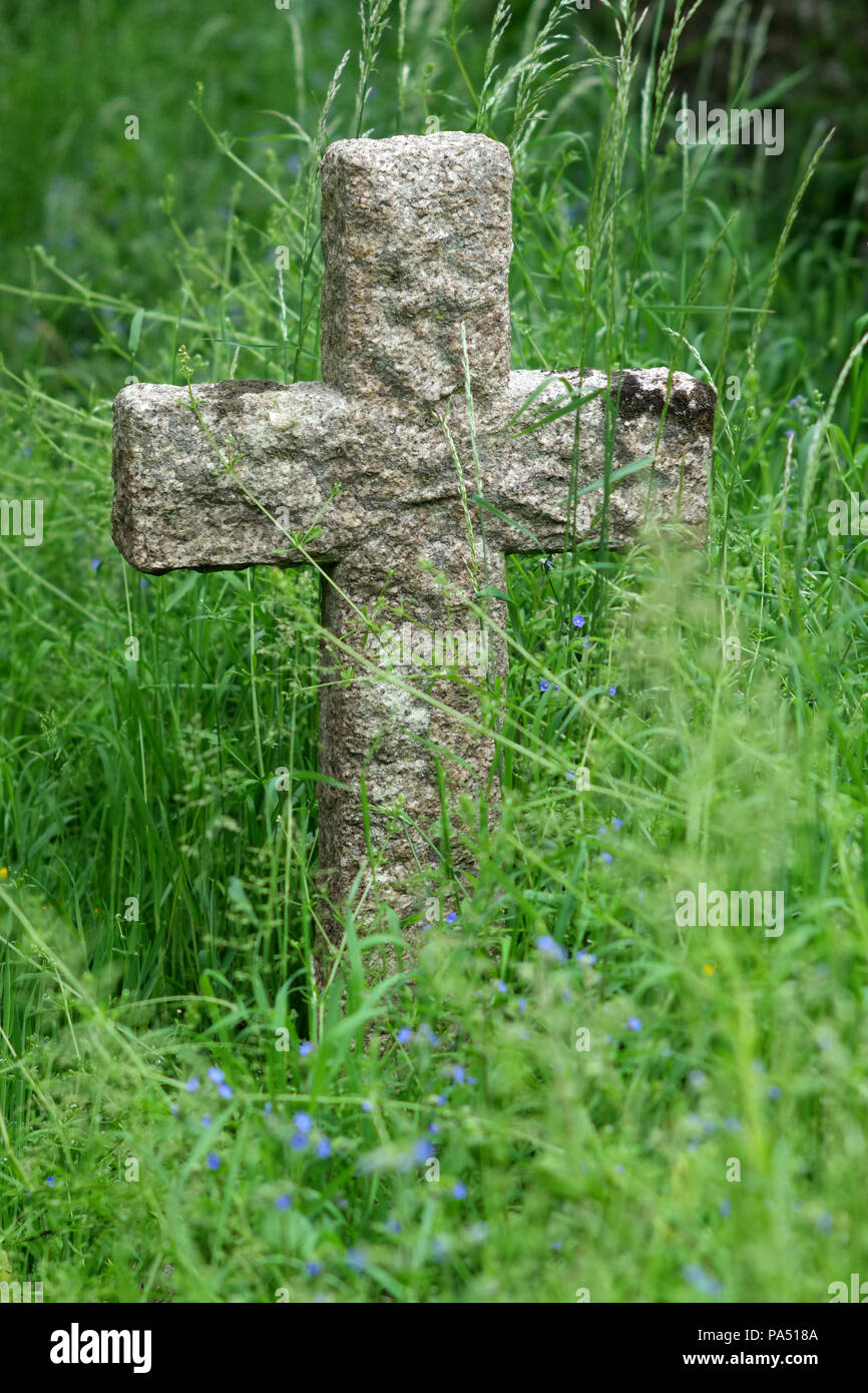 Kruzifix Grabstein in einem üppig bewachsenen Kirche Hof. Stockfoto