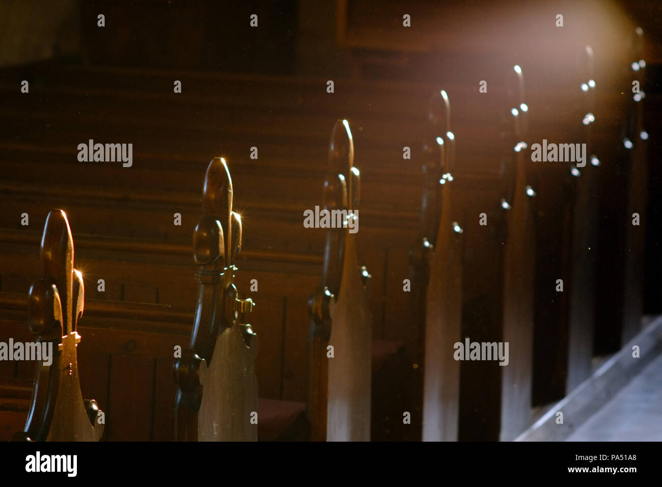 Reihe von kirchenbänken mit fluer de Lys carvng mit einer stimmungsvollen Beleuchtung. Stockfoto