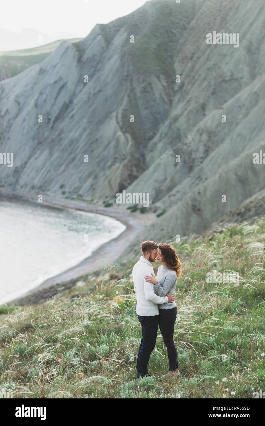 Junges Paar Nordic Walking am Meer mit Blick auf die Berge im Frühling, lässigen Stil Bekleidung Pullover und Jeans Stockfoto