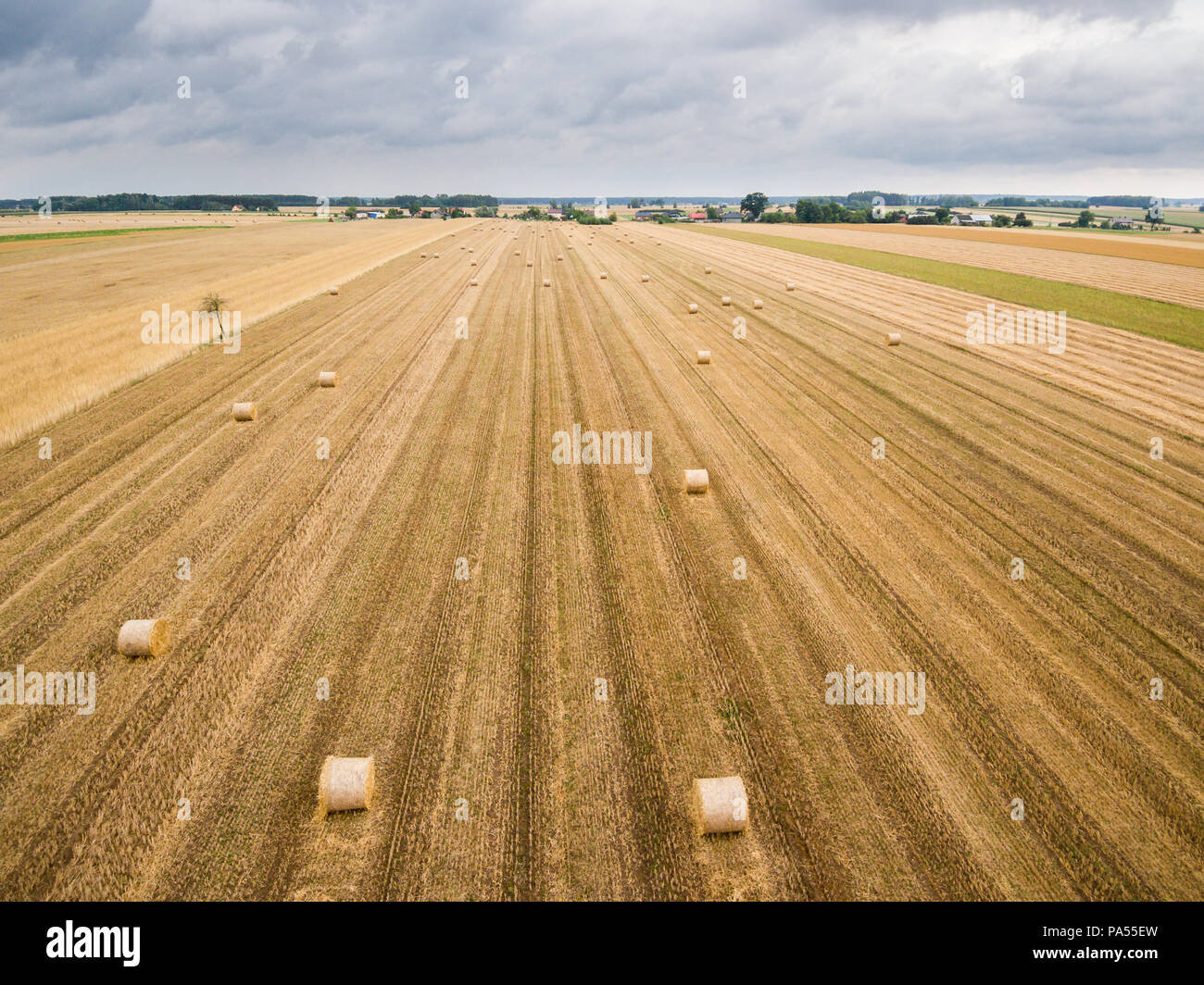 Luftaufnahme von runde Heuballen auf Stoppeln mit einem Dorf im Hintergrund Stockfoto