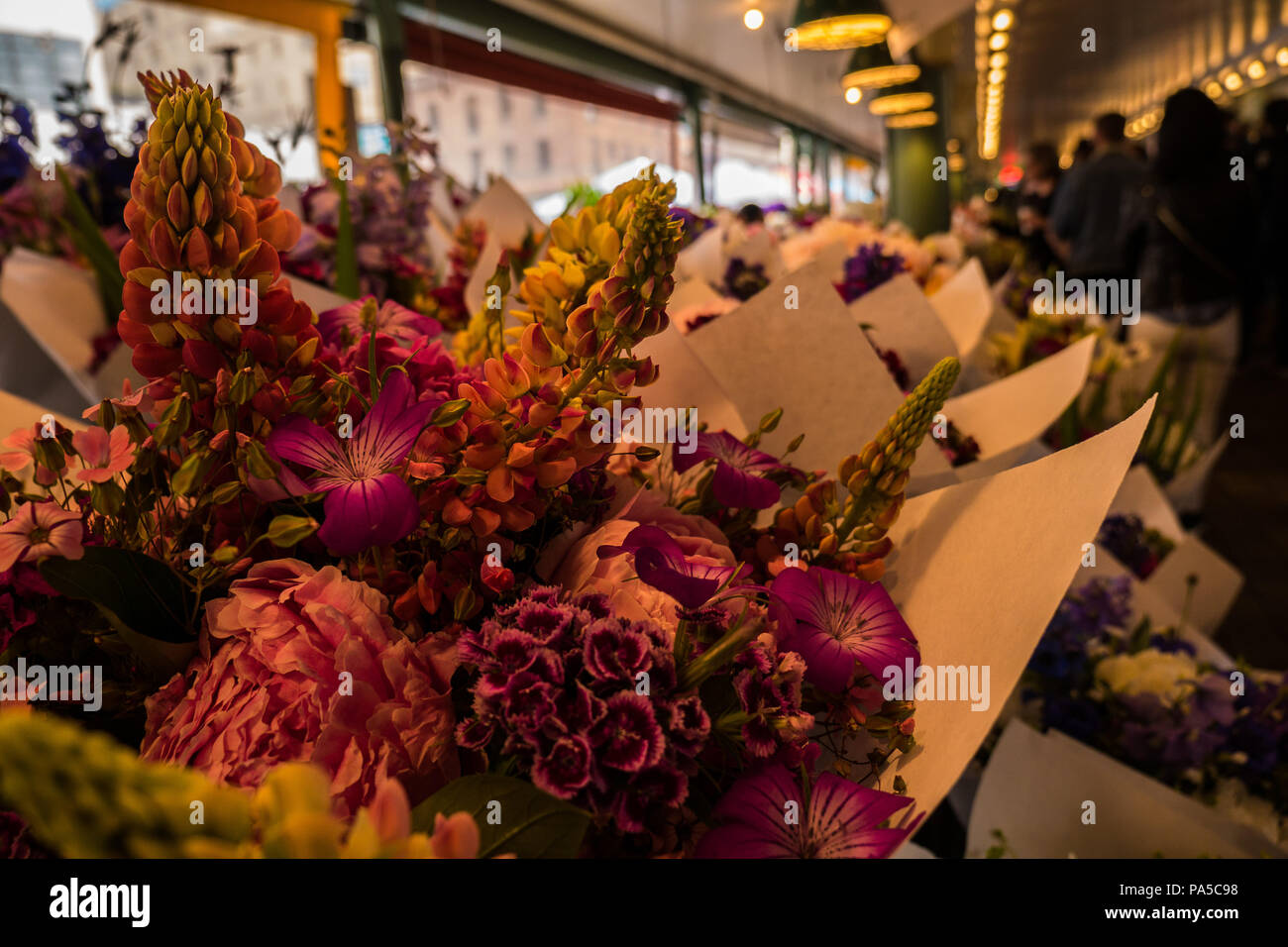 Horizontale Nahaufnahme von schönen, frischen Schnittblumen in Weiß wickeln mit Käufern in den Hintergrund in Blume Abschnitt von der Pike Place Market. Stockfoto